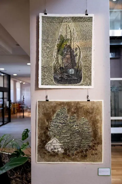 Deux dessins de la série accrochés l'un au-dessus de l'autre sur un pilier de la salle.