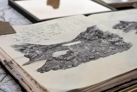 Carnet ouvert : un rocher dessiné à l'encre en hachures serrées.