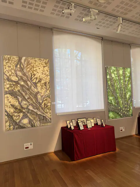 Vue de la salle : deux grands panneaux Habitat, une table rouge couverte de dessins encadrés.