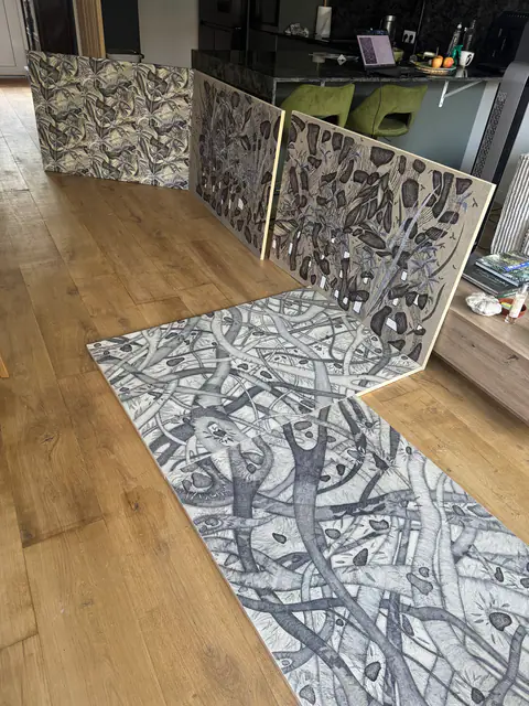 Les panneaux dessinés dressés en paravent, et le panneau posé au sol, dans l'atelier.