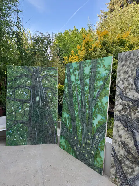 Trois grands panneaux de la série Habitat posés debout dans un jardin, entre les arbres.