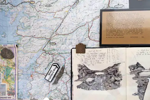 Carte de randonnée dépliée, carnets de dessin et petits objets ramassés en chemin.