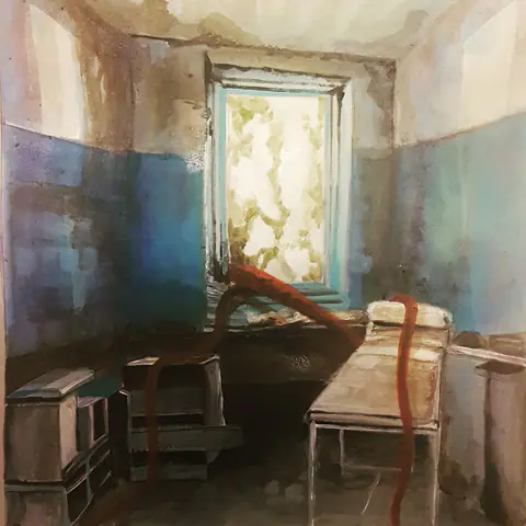 Chambre aux murs bleus ; une racine rouge passe près d'un lit en fer.