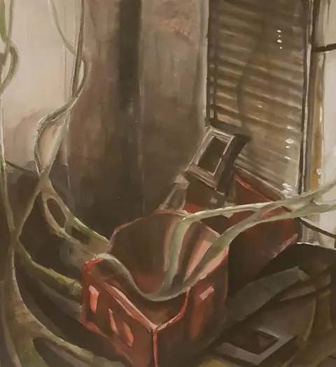 Caisse rouge entourée de racines pâles, dans une pièce sombre.