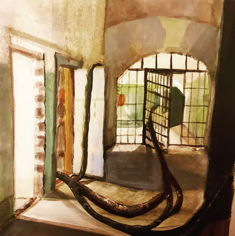 Porte grillagée en arc ; des racines sombres sur le sol.