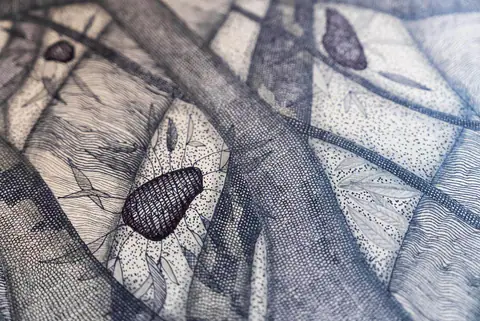 Gros plan sur une graine dessinée au milieu des branches du panneau du sol.